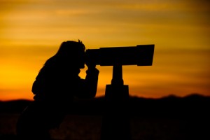 Woman Looking Through Telescope At Sunset